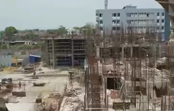 Construction site of Vicint Marquis with early structure works, reinforcement bars and a concrete frame rising, and neighbouring buildings behind
