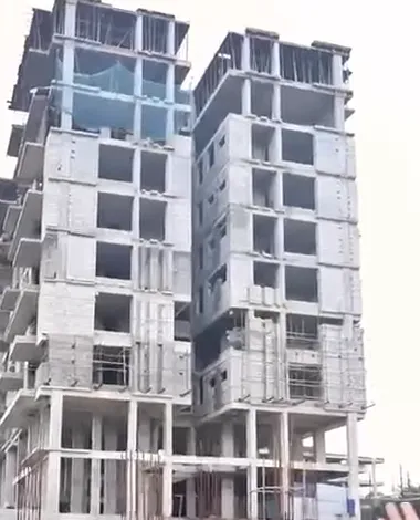 The Vicint Marquis residential tower under construction: a multi-storey concrete and blockwork frame with open floors, seen from below